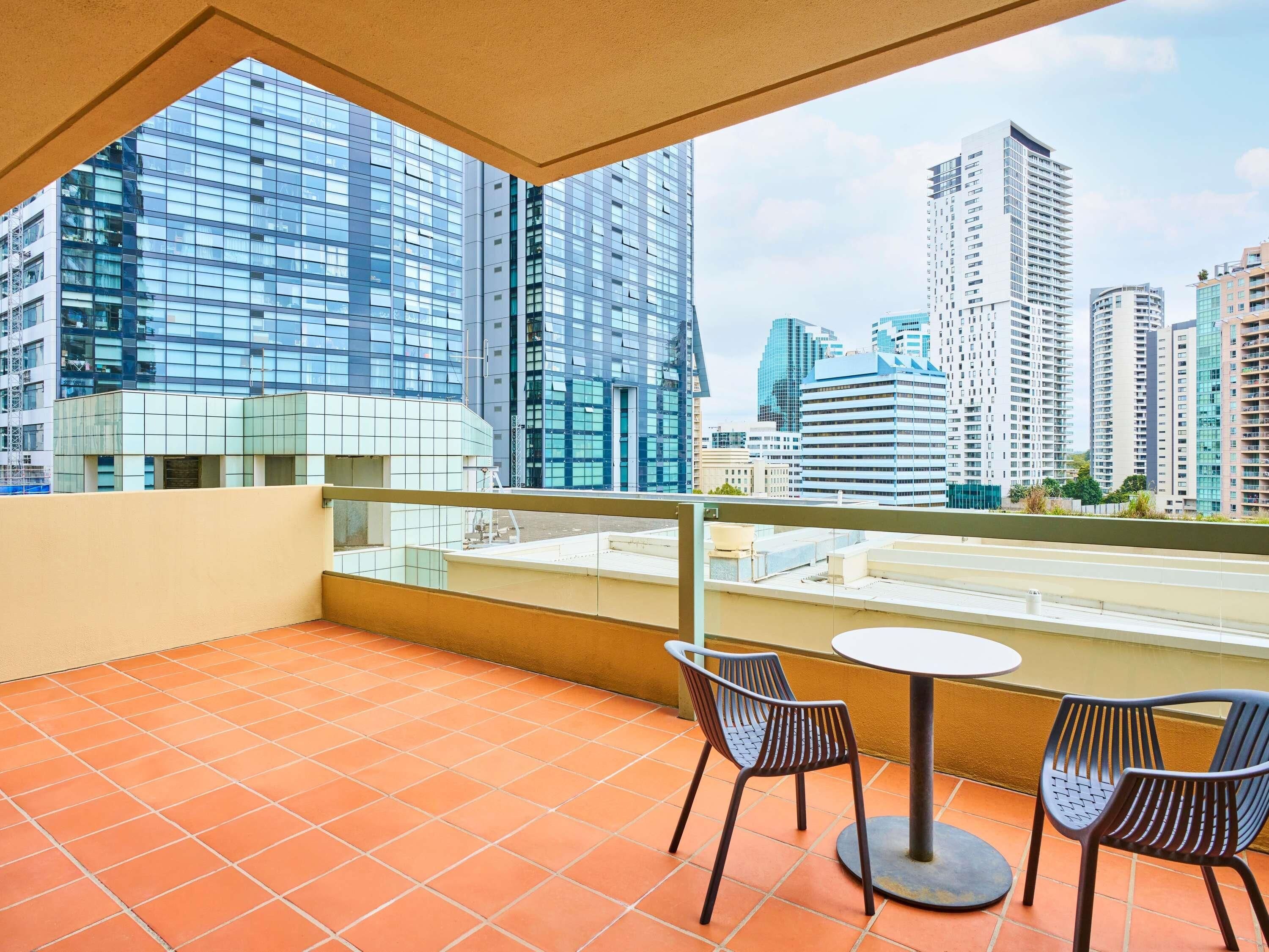 A balcony with a tiled floor, two chairs, and a table.