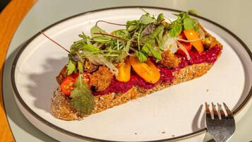 Ein Teller mit einem Sandwich, belegt mit verschiedenen Gemüsesorten und Salat, dazu eine Gabel.