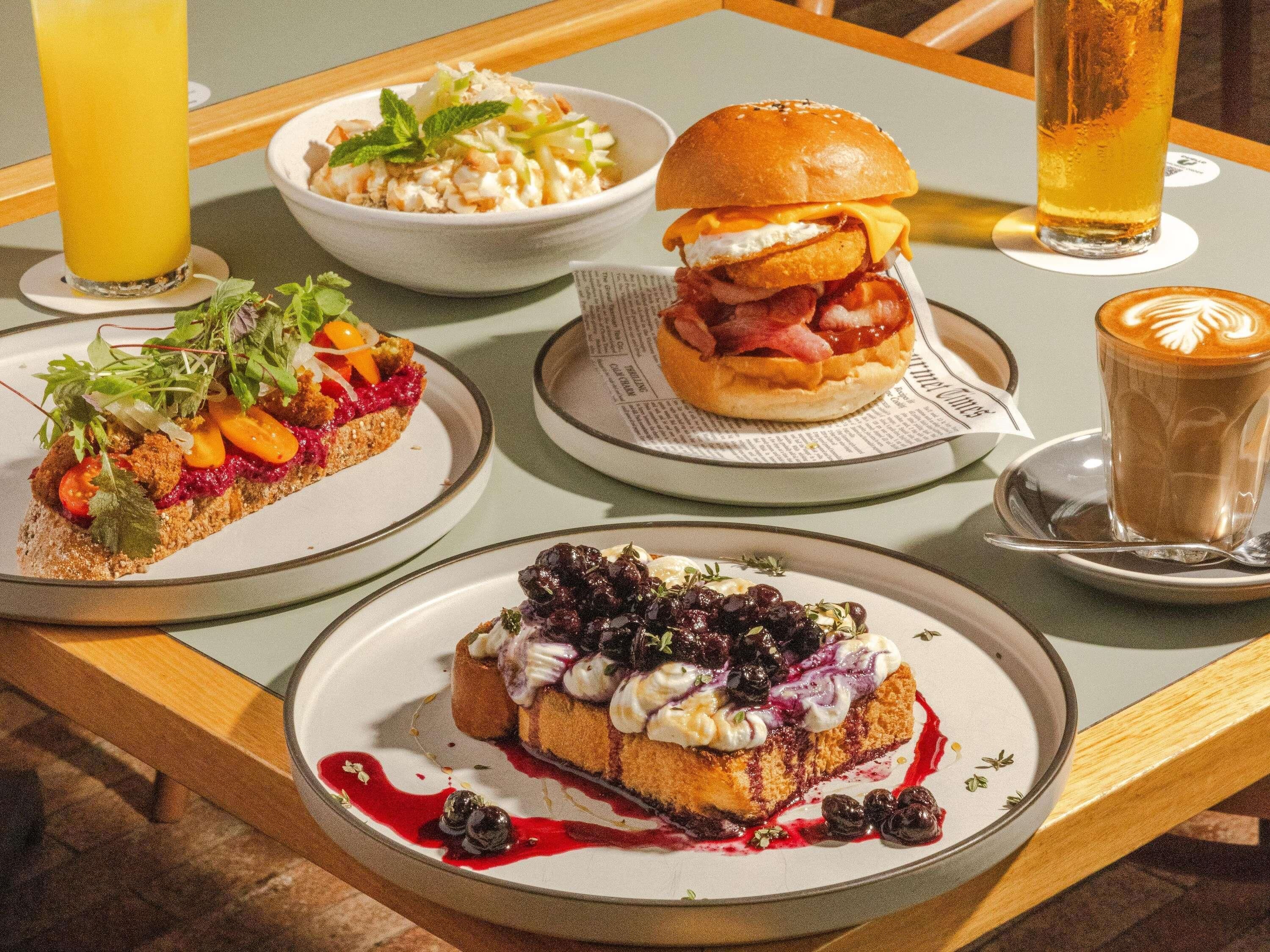 Una mesa con diversos platos, incluyendo un sándwich, un postre y una bebida.
