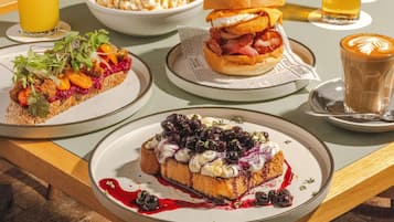 A table with a variety of dishes including a sandwich, a dessert, and a drink.
