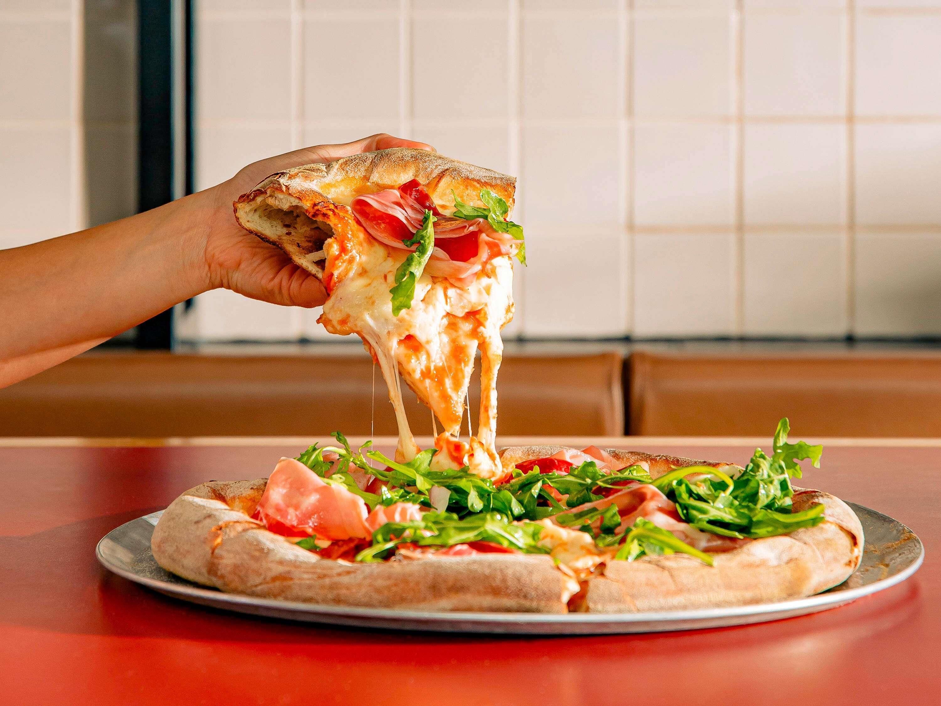 A pizza with toppings on a metal plate on a table.