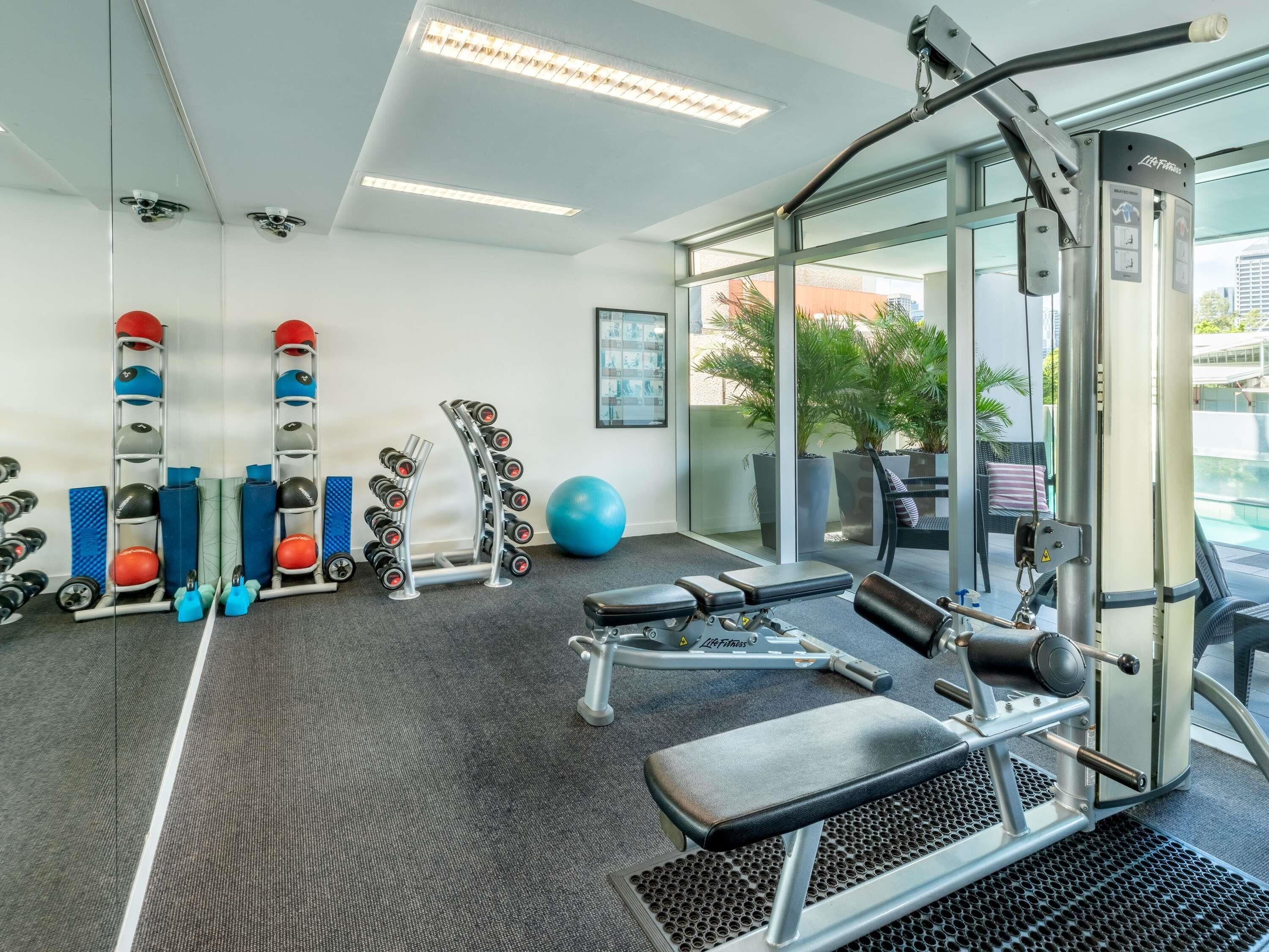 A gym with exercise equipment, a bench, and a large exercise ball.
