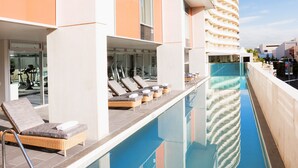 A poolside area with lounge chairs and a clear blue pool.