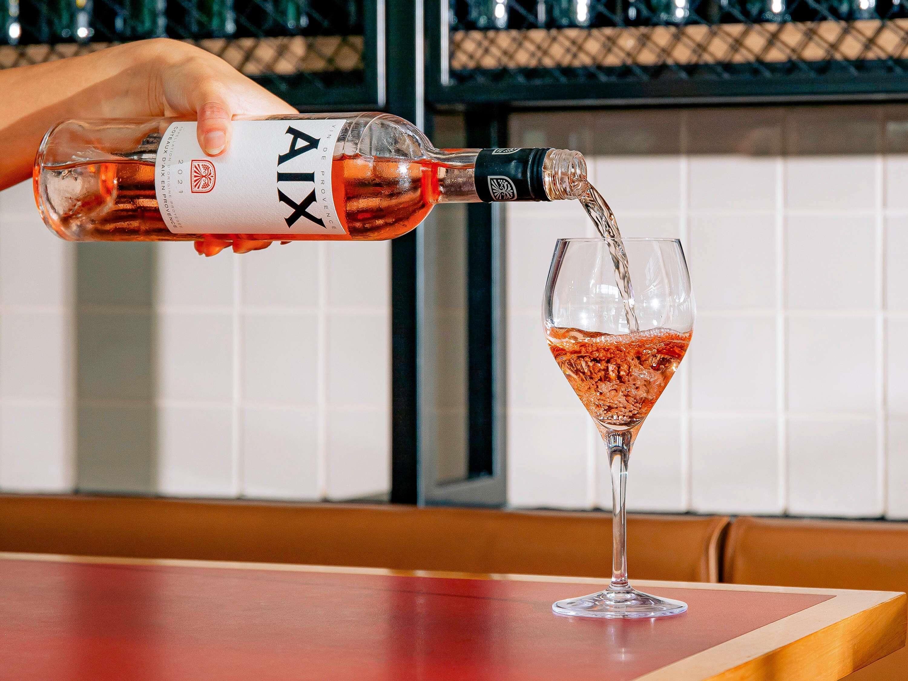 A bottle of AIX wine being poured into a glass.