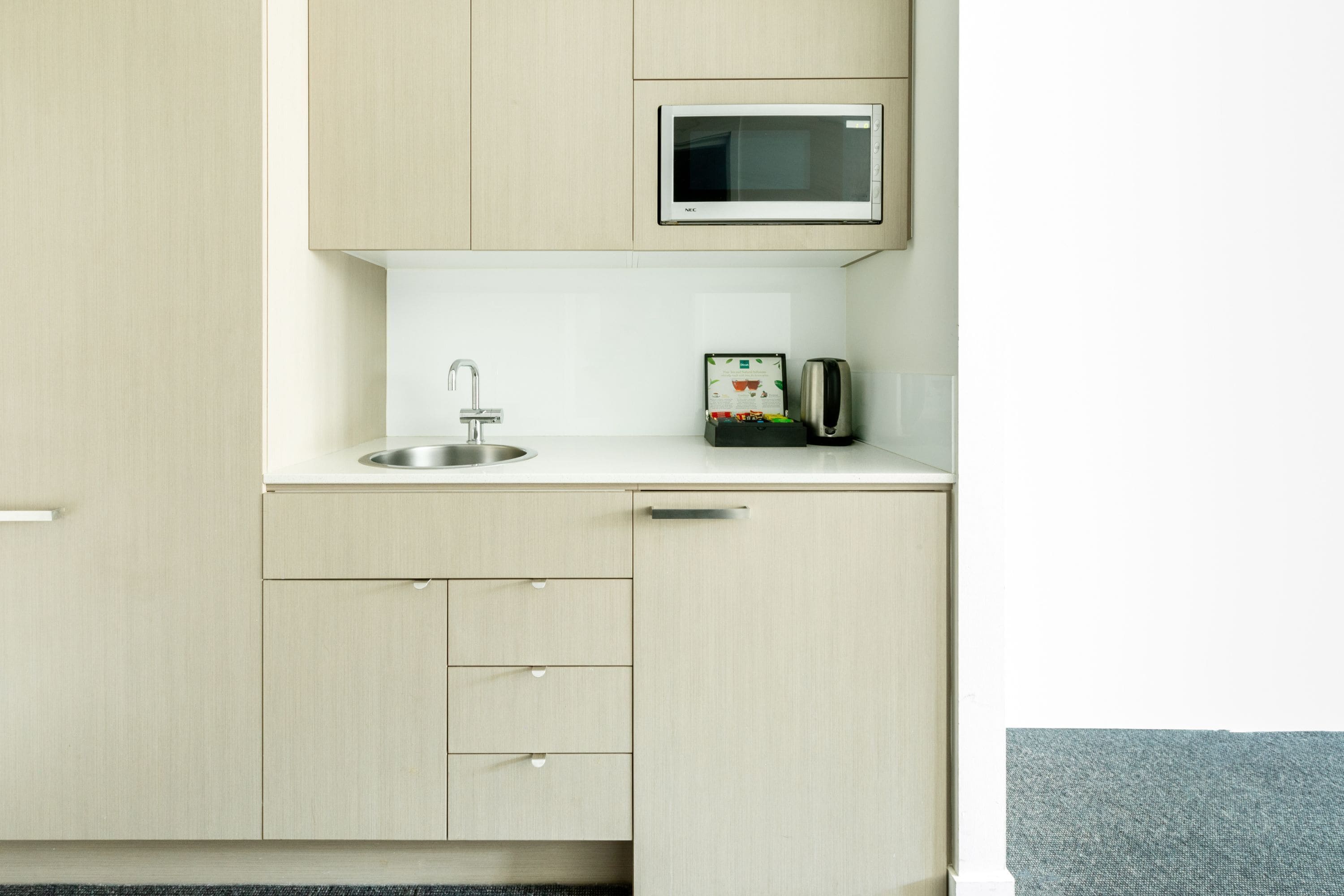 A compact kitchenette with a microwave, sink, and a toaster.