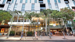 A modern building with a glass facade, outdoor seating area, and a sign for 'Manta'.