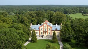 Ein großes, historisches Herrensitz, umgeben von üppigem Grün und einem gepflegten Rasen.