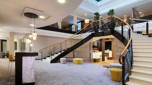 A spacious lobby with a modern staircase, a reception desk, and seating areas. - Cologne Marriott Hotel (Cologne)