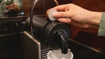 Eine Hand bedient eine Kaffeemaschine und füllt eine Tasse mit Kaffee.