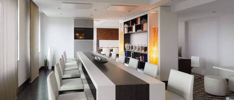A modern hotel lobby with a long reception desk, white chairs, and a patterned rug.