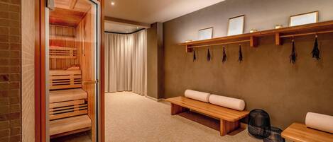Un sauna con bancos, sauna de madera y estante con toallas.