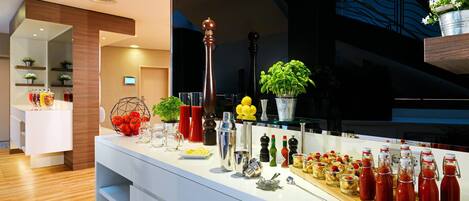 A modern bar area with a variety of drinks and snacks, a tall wooden column, and a potted plant.