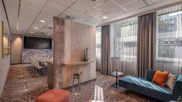 Un moderno vestíbulo de hotel con zona de estar, televisor y espacio para comer.