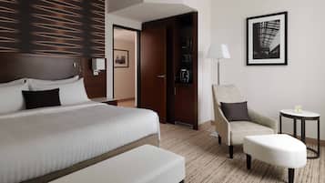 A hotel room with a large bed, a chair, a small table, and a framed picture on the wall.