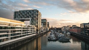 A modern urban waterfront with high-rise buildings, a marina with boats, and a clear sky. - Cologne Marriott Hotel (Cologne)