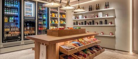 A modern retail space with refrigerated beverage displays, snack shelves, and a wooden counter with drawers.