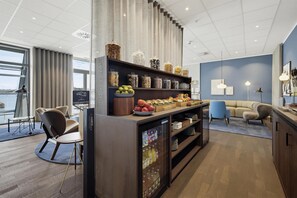 Habitación de hotel moderna con kitchenette, zona de estar y vistas a la ciudad.