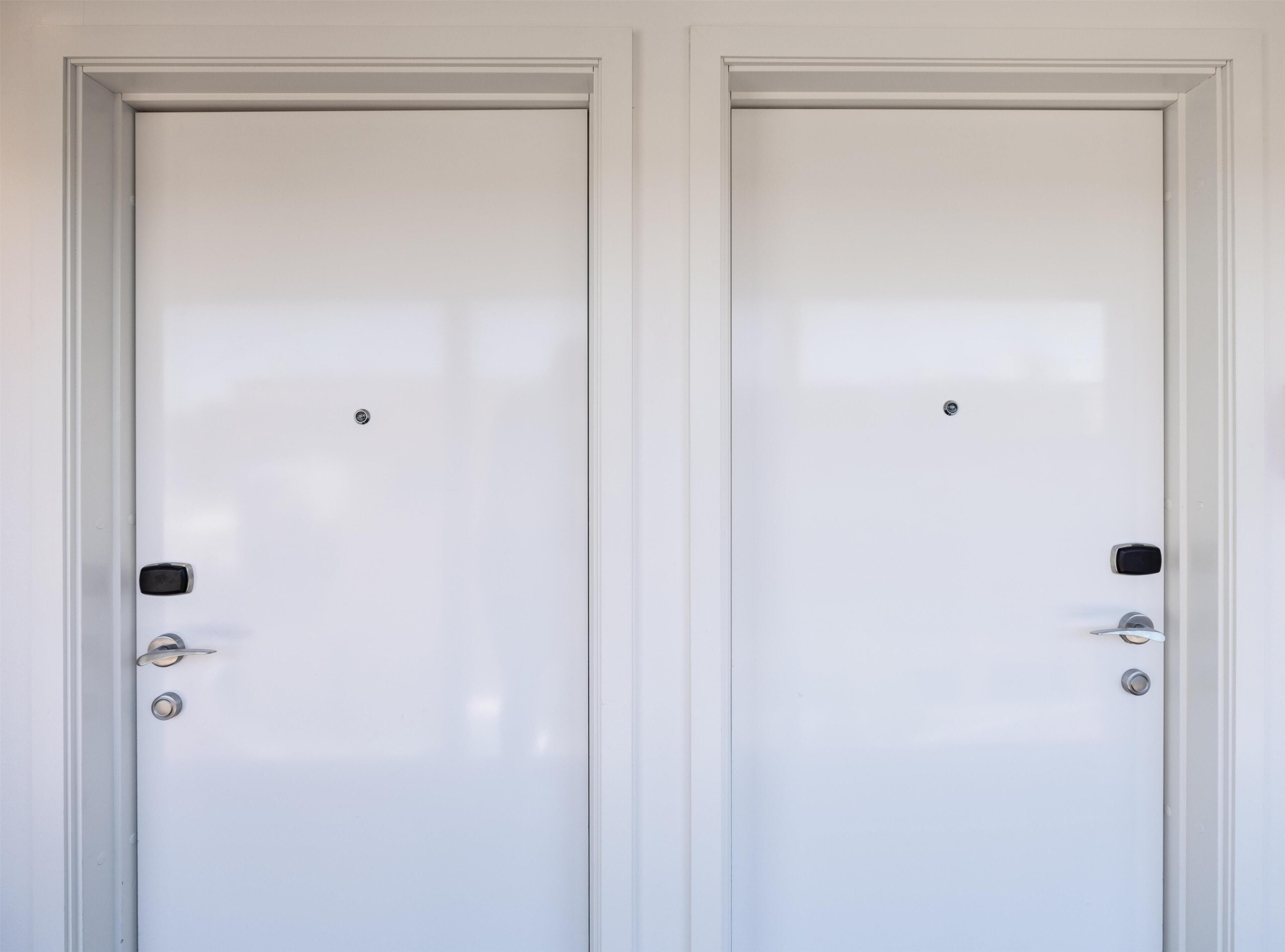 Two white doors with a simple design, a small lock, and a handle on the left door.