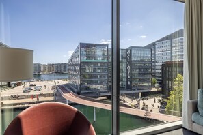 Een moderne hotelkamer met een groot raam met uitzicht op een stadslandschap, inclusief een brug en een waterkant.