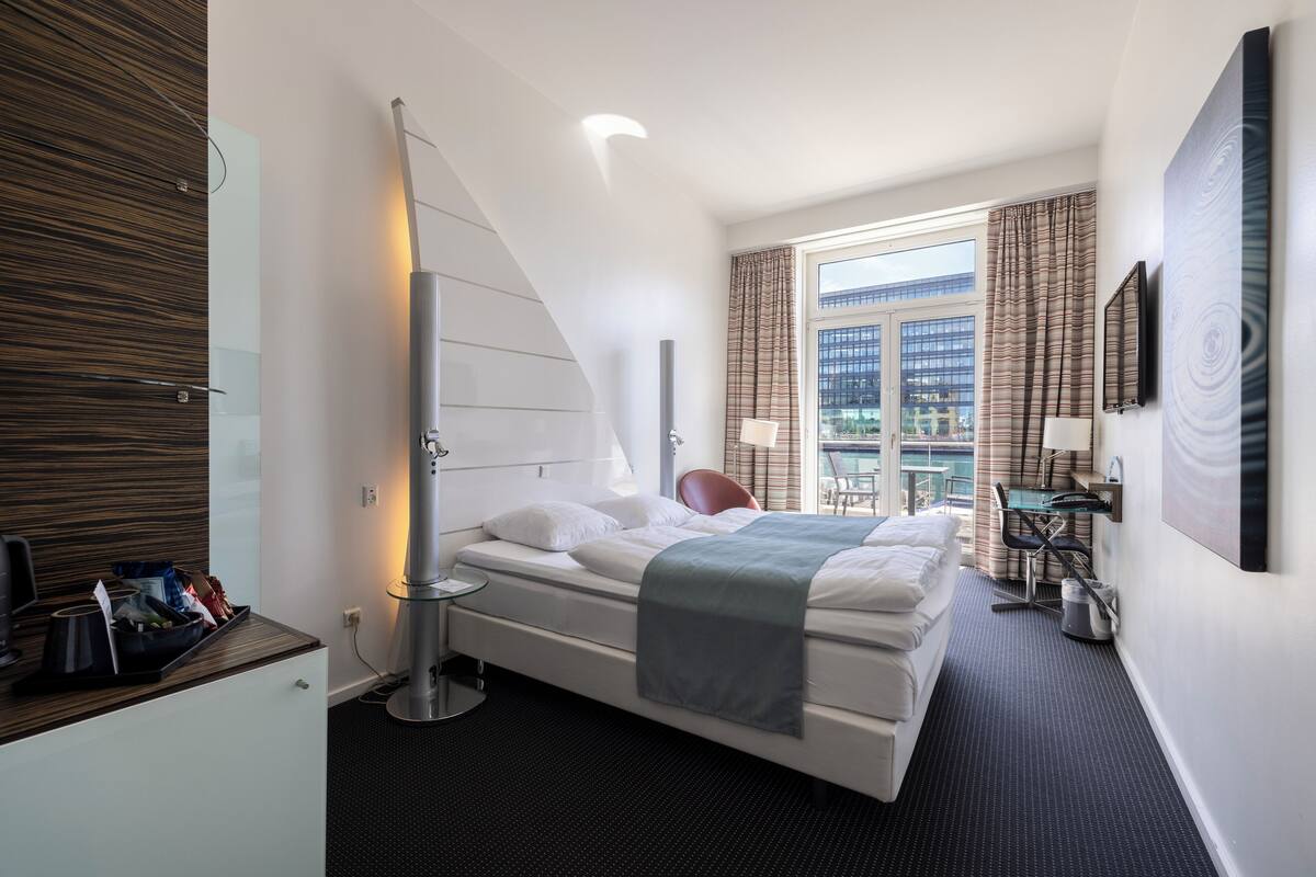 Une chambre d’hôtel moderne, équipée d’un lit, d’un bureau et offrant une vue sur la ville.