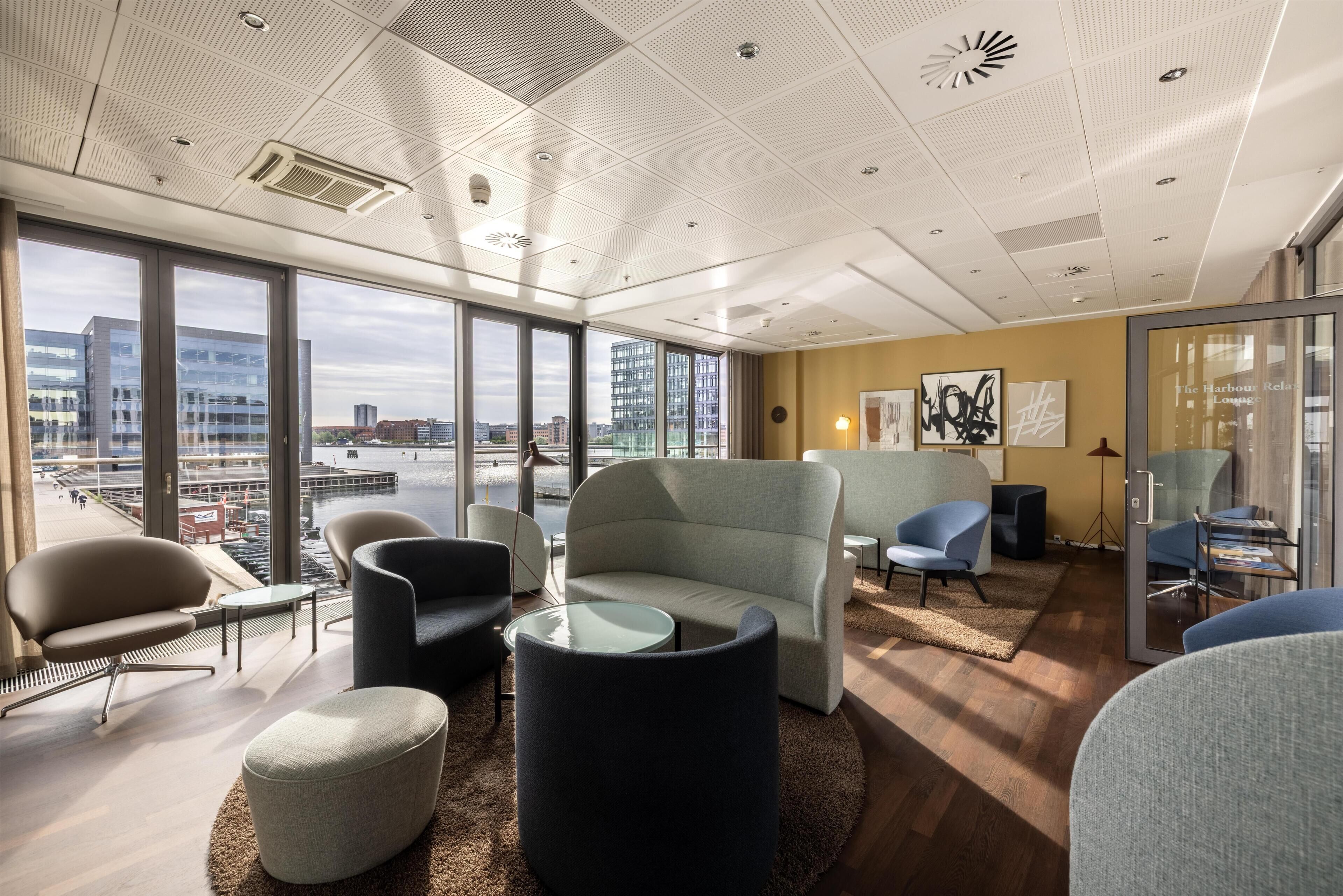 Un espacio de oficina moderno con ventanas amplias, mobiliario contemporáneo y vistas a la ciudad.
