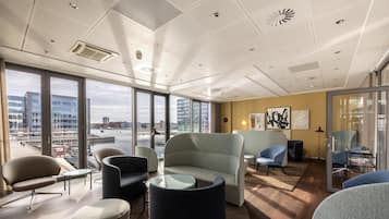 Un espacio de oficina moderno con ventanas amplias, mobiliario contemporáneo y vistas a la ciudad.