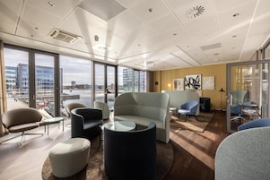 Un espace de bureau moderne doté de grandes fenêtres, de mobilier contemporain et offrant une vue sur la ville.