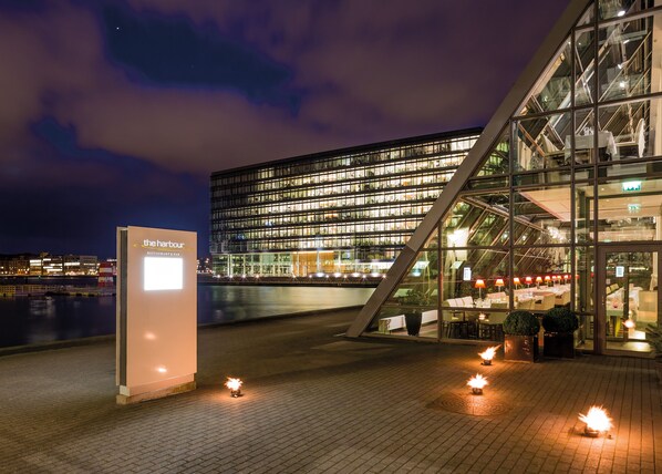 Ein modernes Gebäude mit Glasfassade und einem Schild für 'The Harbour Restaurant & Bar'.