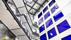 A multi-level building with a modern architectural design, featuring glass railings and a series of windows.