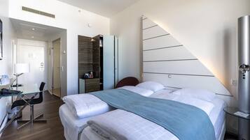 Une chambre d’hôtel moderne avec un grand lit, un bureau avec une chaise et une armoire.