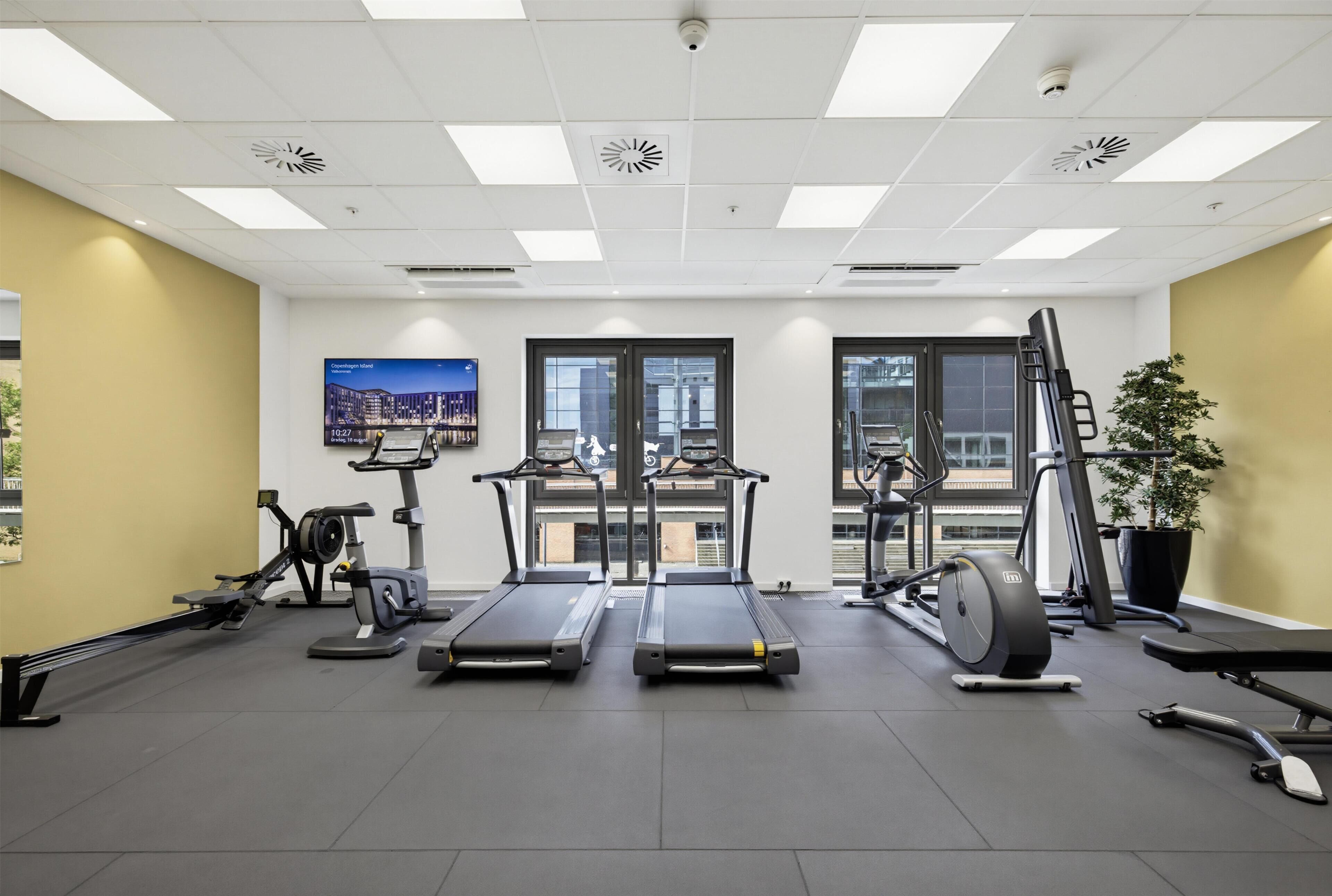Un gimnasio con cintas de correr, bicicletas estáticas y equipamiento de ejercicio.