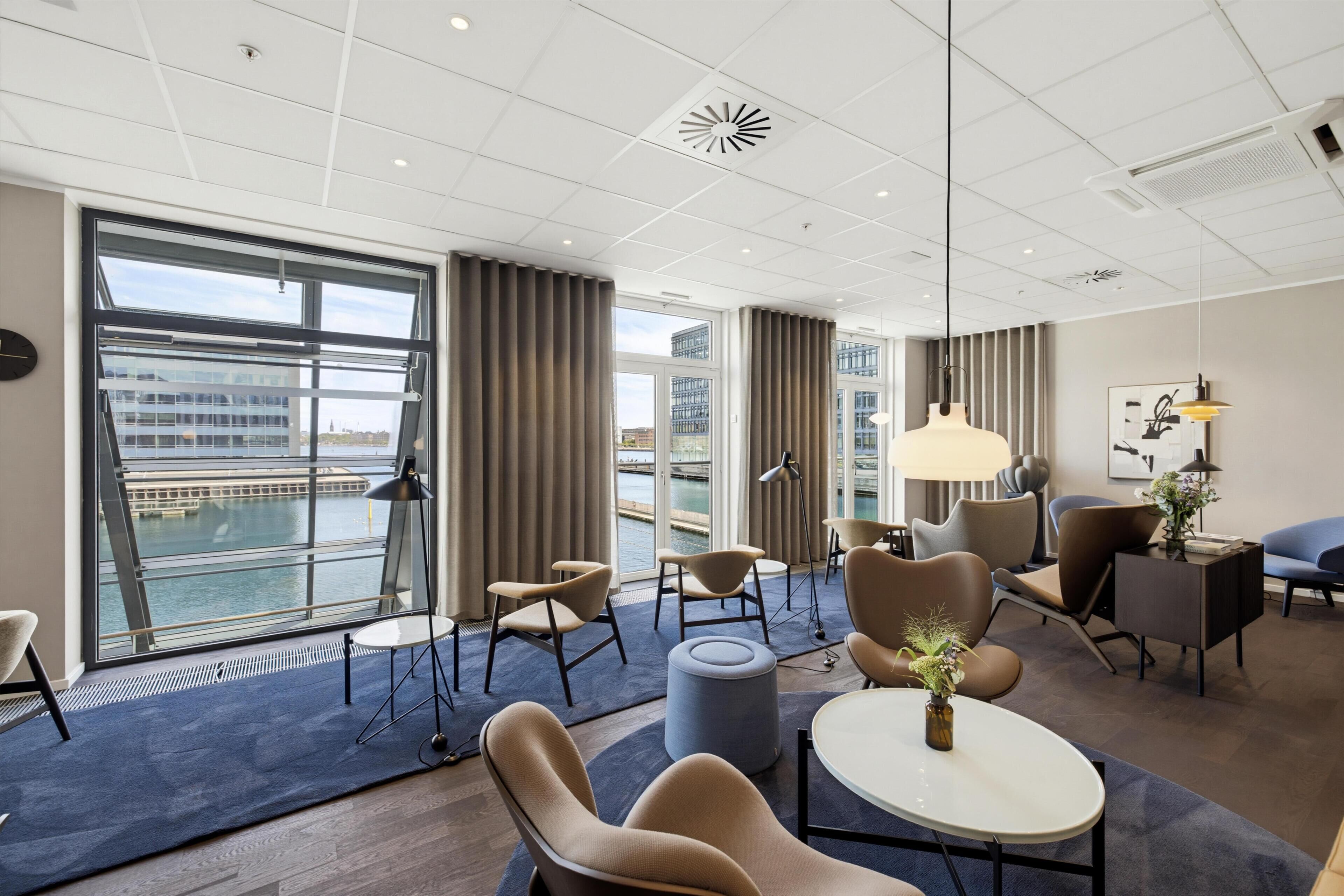 Ett modernt hotellrum med stora fönster, utsikt över stadsbilden och samtida möbler.