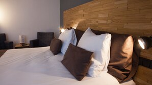 A neatly made bed with white and brown bedding, a wooden headboard, and a bedside table with a lamp. - Hotel Bieze (Borger)