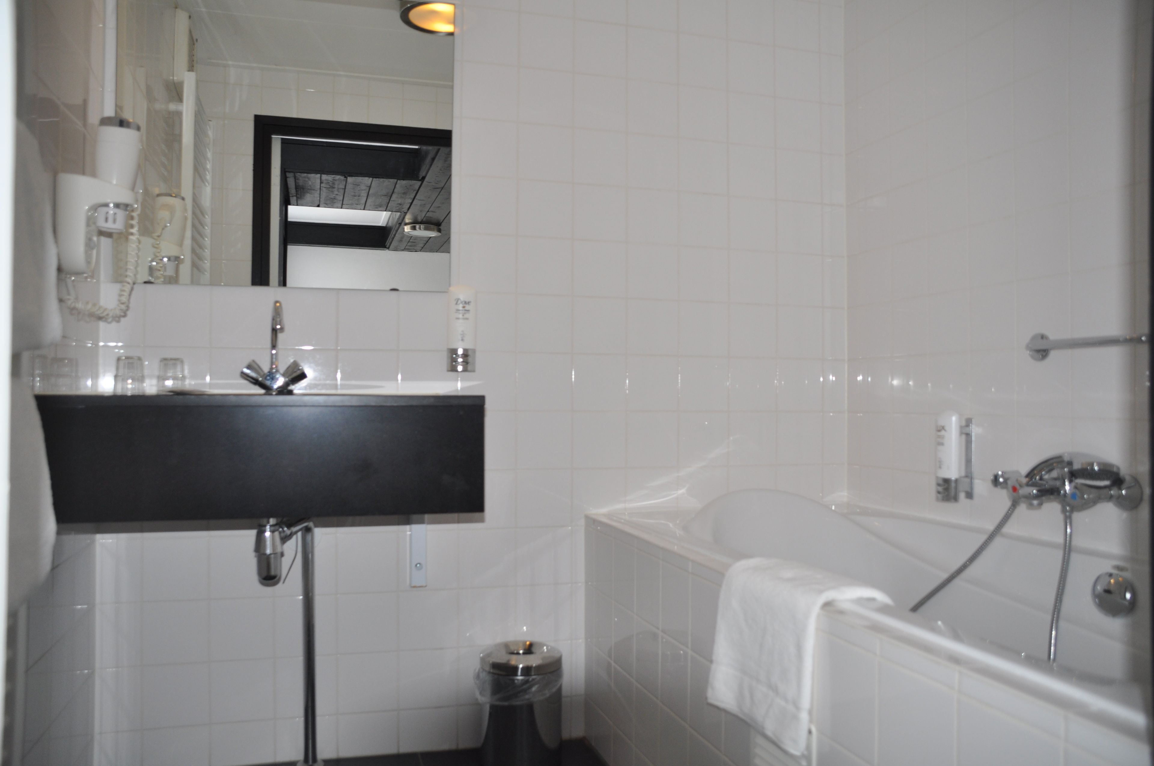 A bathroom with a black sink, a mirror, a white toilet, and a bathtub.