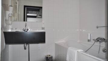 Ein Badezimmer mit einem schwarzen Waschbecken, einem Spiegel, einer weißen Toilette und einer Badewanne.
