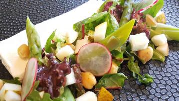 A salad with various vegetables and cheese on a textured surface.