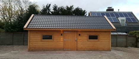 A wooden shed with a tiled roof, two windows, and a door.