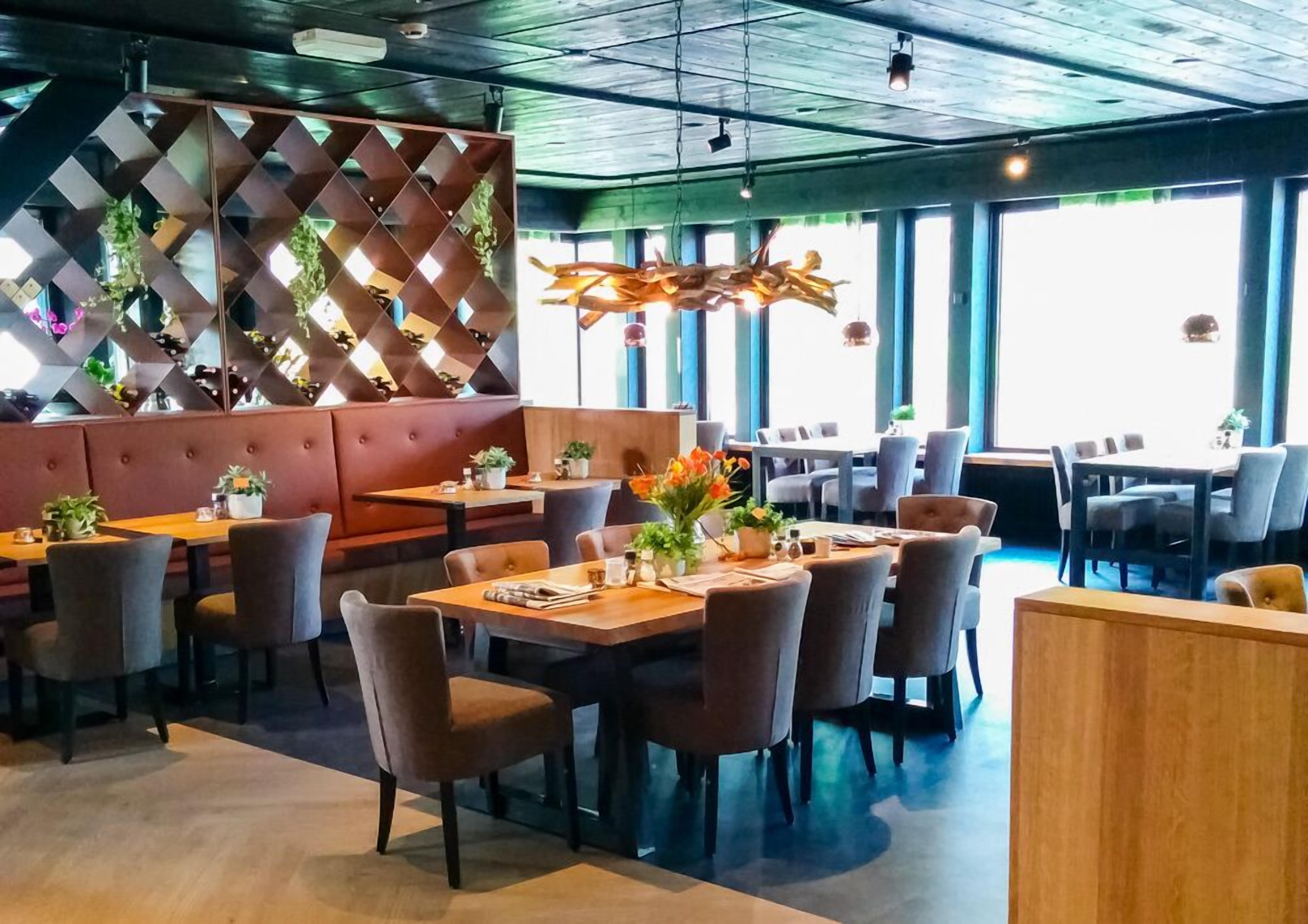 A modern restaurant interior with booths, tables, and chairs.
