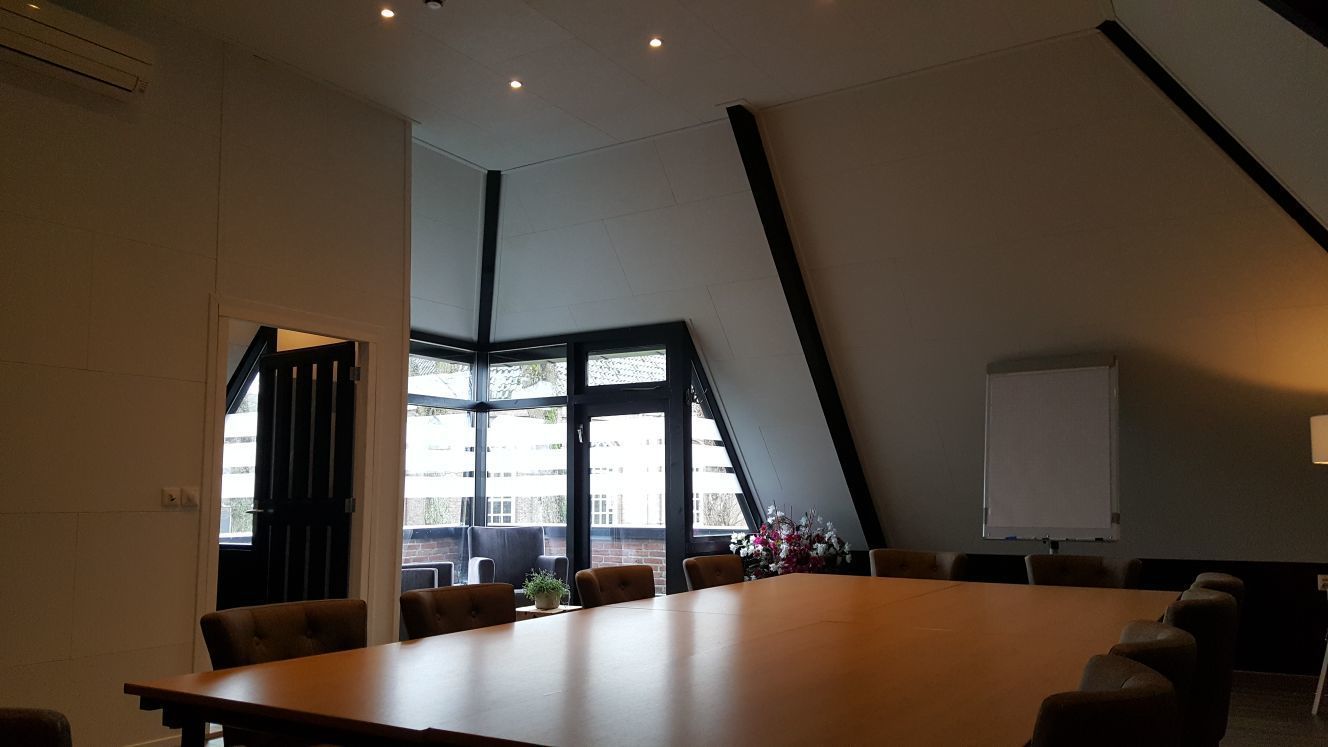 A conference room with a long table, several chairs, a whiteboard, and large windows with a view of buildings outside.