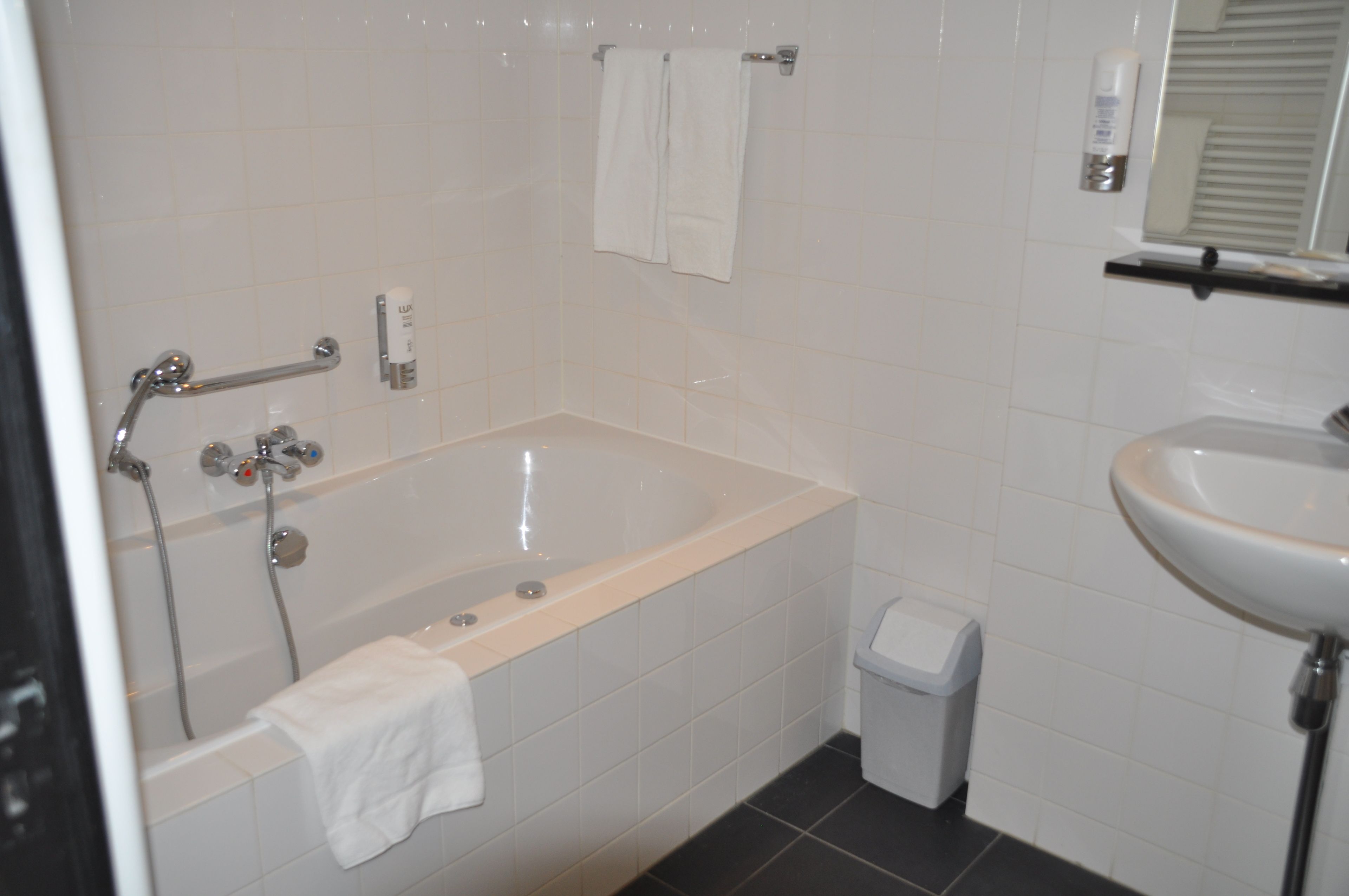 Une salle de bain avec une baignoire, un lavabo et une poubelle.