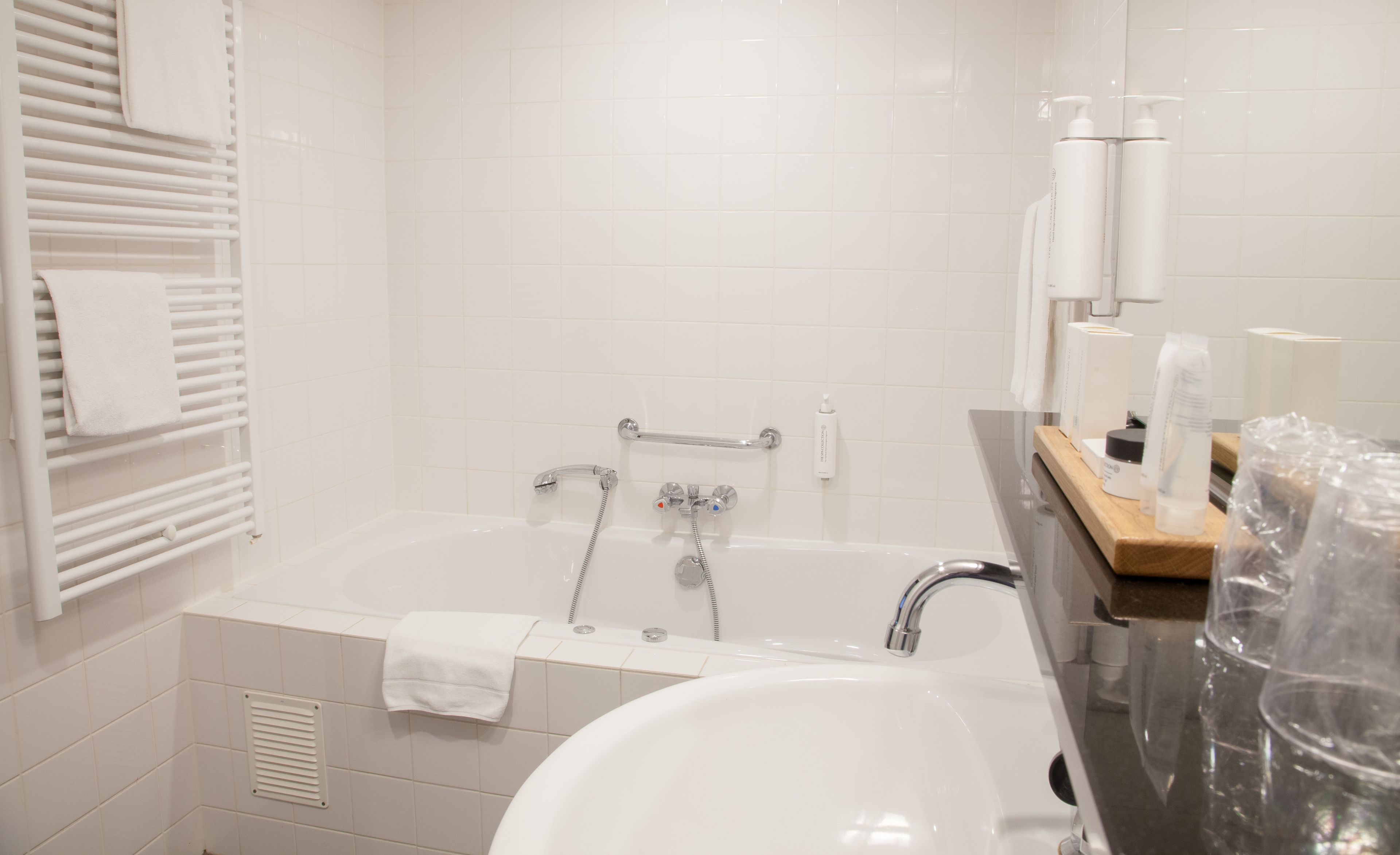 Un baño moderno con bañera, lavamanos y tocador con artículos de aseo.