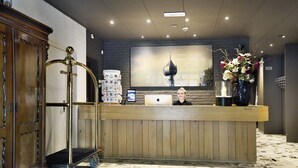 A reception desk with a wooden counter, a digital screen, and a large framed picture on the wall. - Hotel en Restaurant Wesseling (Dwingeloo)