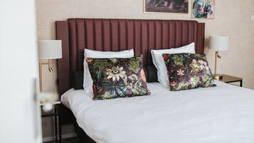 A hotel room with a large bed, two side tables with lamps, and floral-patterned pillows.