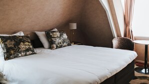 A hotel room with a bed, a nightstand, a lamp, a chair, and a window with curtains. - Hotel en Restaurant Wesseling (Dwingeloo)