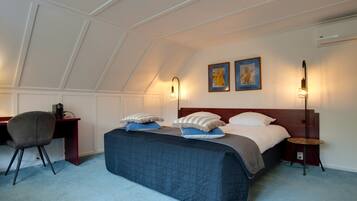 A bedroom with a bed, desk, chair, and two wall-mounted lamps.