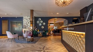 A hotel reception area with a modern design, including a reception desk, seating area, and decorative elements. - Fletcher Boshotel de Lochemse Heuvels (Barchem)