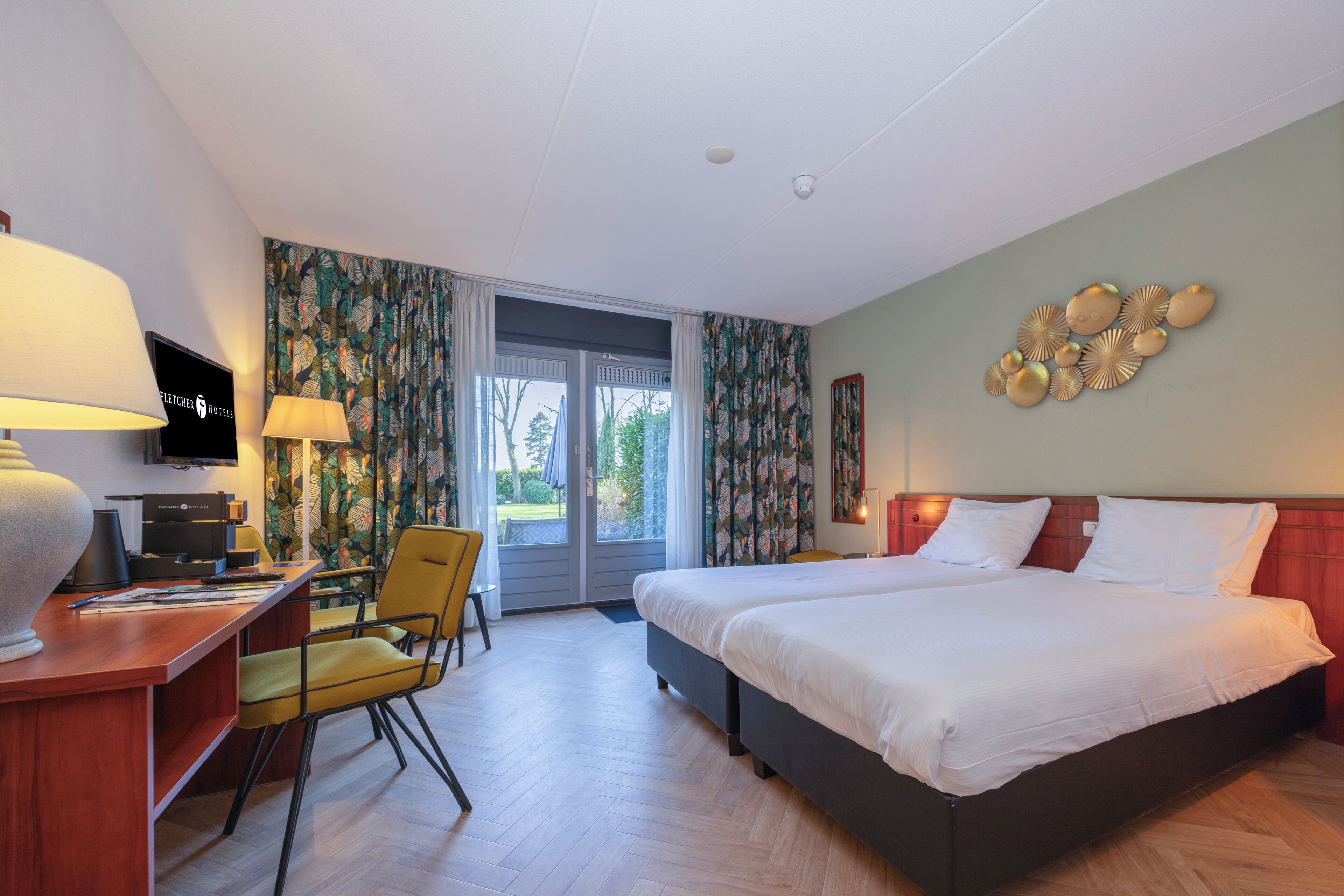 A hotel room with a bed, desk, chair, and a television.