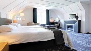 A hotel room with a large bed, a desk, a television, and a fireplace. - Fletcher Boshotel de Lochemse Heuvels (Barchem)