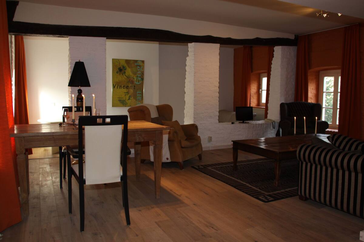 Un salon comprenant une table à manger en bois, deux chaises, un canapé et un téléviseur.