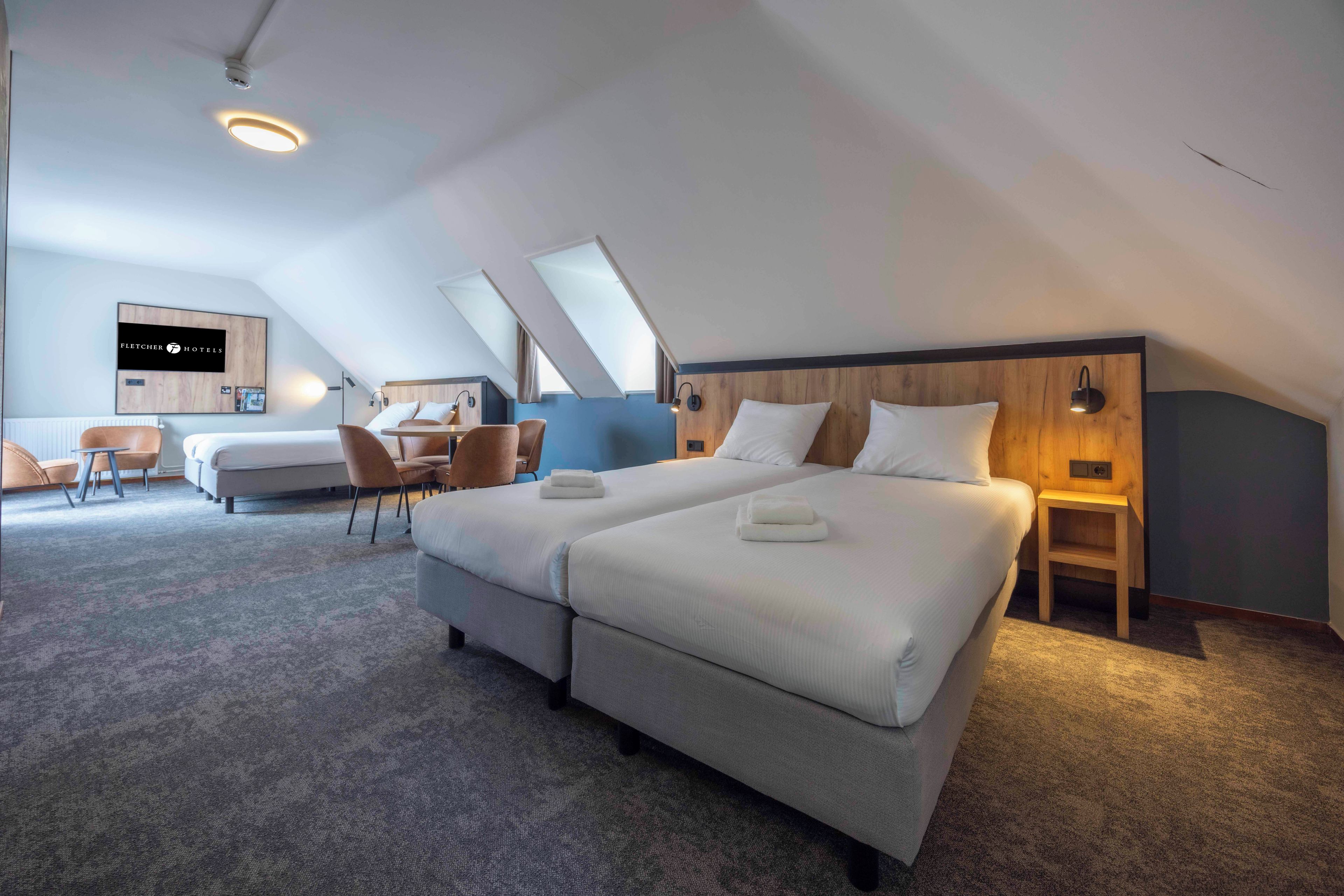 Una habitación de hotel moderna con una cama grande, un escritorio y una zona de estar.
